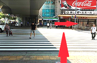 大きな横断歩道がございますので横断歩道を渡り、直ぐに右（矢印の方向）にお進みください。